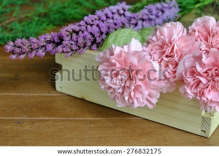 Sweet Pink Carnation and purple flowers in light color wood tray