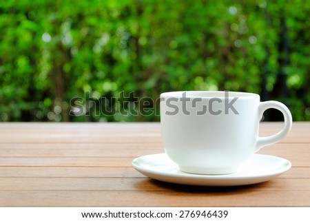 Relax with a cup of coffee at home with blur green garden background