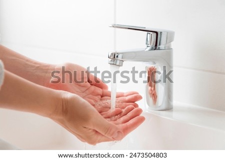 Foto Bild Hände im Strahl der Wasserpumpe mit Blick auf unscharfem Kopfsteinpflaster