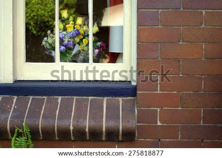 a window on a brick wall with a beautiful vase of flowers and a table lamp inside at the Rocks, Sydney