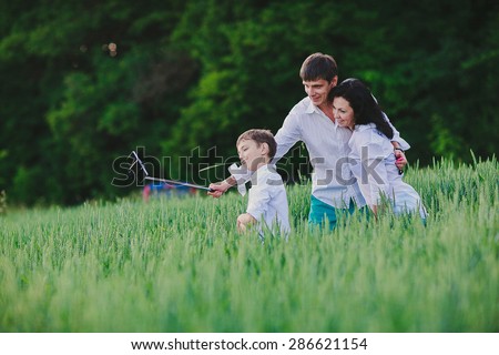 a happy family is taking photos of themselves with the help of monopod in the green field