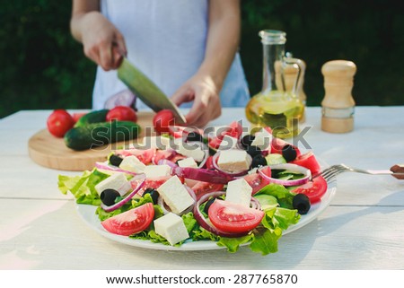 a chef is cooking, greek salad, olive oil and some spices on a white wooden table