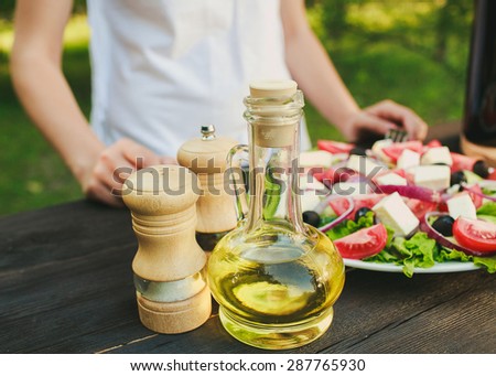 a chef is trying Geek salad, olive oil, there are spices and wine on the table