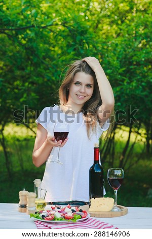a girl is drinking wine at the dinner table in the garden