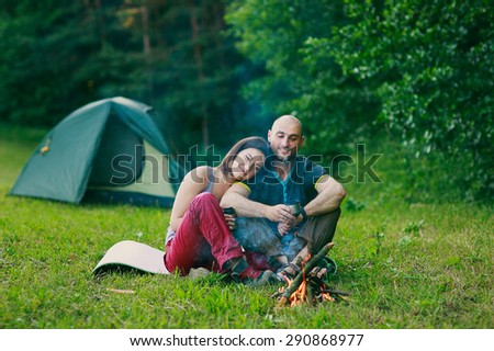a couple in love is sitting at the fire and hugging