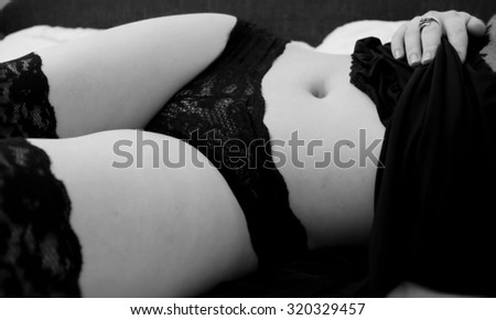 Young brunette in sexy lingerie lying on the couch in the bedroom black and white shot