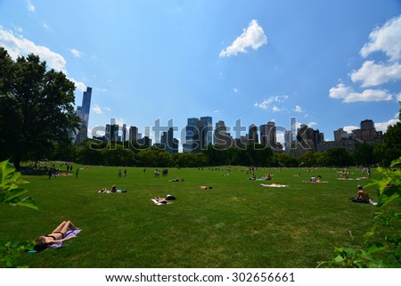 Summer in the city/ New York City Central Park / new york, USA - August 1, 2015: Girl in bikini in New York City Manhattan Central Park with cloud and blue sky and people in lawn