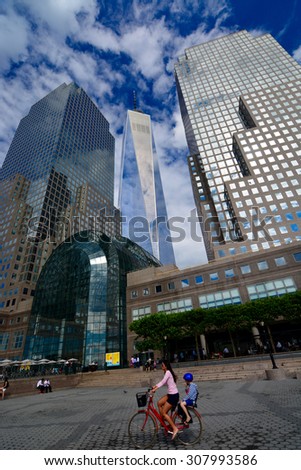 New York City, One World Trade Center/ Freedom tower/ New York, USA - June 29, 2015: Lady riding her bike with child on back in front of the Freedom Tower, New York City, One World Trade Center