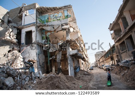 GAZA, PALESTINIAN TERRITORY - DECEMBER 2: A child passes a bombed-out residential block in the Al-Zeitoun neighborhood of Gaza City, December 2, 2012.