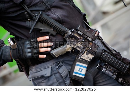 JERUSALEM - OCTOBER 4: An Israeli policeman is armed with an assault rifle decorated with the Israeli flag during the annual Jerusalem March, Oct. 4, 2012.
