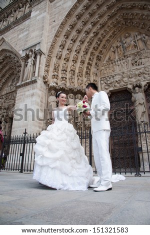 PARIS - JUNE 27: A bride and groom pose for photos in front of the Notre Dame de Paris cathedral, Paris, France, June 27, 2013.