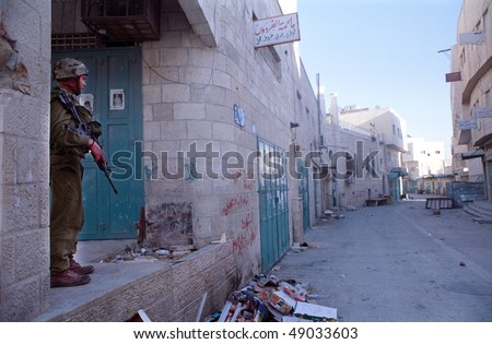 BETHLEHEM, PALESTINIAN AREAS - MAY 28: A soldier of the Israeli Defense Forces patrols the West Bank town of Bethlehem during a curfew imposed on its Palestinian residents May 28, 2002 in Bethlehem.