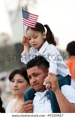 WASHINGTON, DC - MARCH 21: A girl and her father stand with some 200,000 immigrants\' rights activists flood the National Mall to demand comprehensive immigration reform on March 21, 2010 in Washington DC.