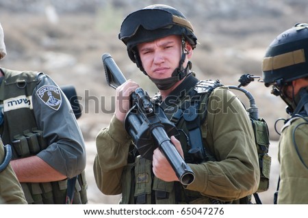 AL-WALAJA -  NOVEMBER 13: An Israeli soldier with a tear gas gun stands by during a protest against Israel's separation wall on Nov. 13, 2010 in Al-Walaja.