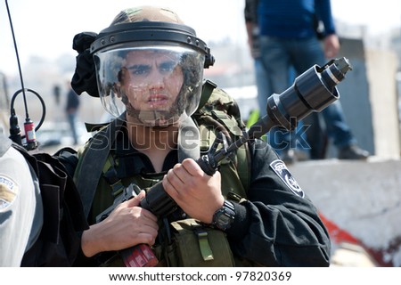 KALANDIA, OCCUPIED PALESTINIAN TERRITORIES - MARCH 8: An Israeli soldier holds a U.S.-made tear gas grenade launcher mounted on an M16 rifle during demonstrations  on March 8, 2012 in Kalandia