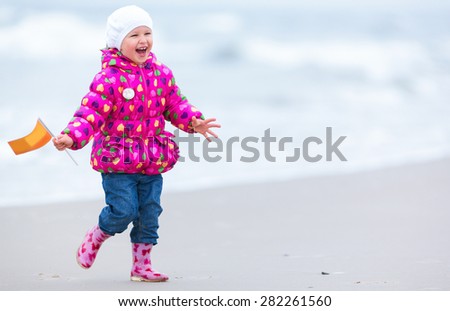Cute girl is running on the beach (Late fall. Klaipeda, Lithuania).