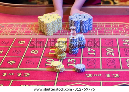 Casino American Roulette gambling table with a playing chips on the layout. Croupier is doing payout.