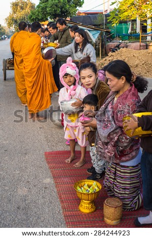 NONGKAI, THAILAND - 01 January, 2015: in an early morning after a long wait, locals give food offerings to Buddhist monks on the road as their religion tradition for the beginning of a new year
