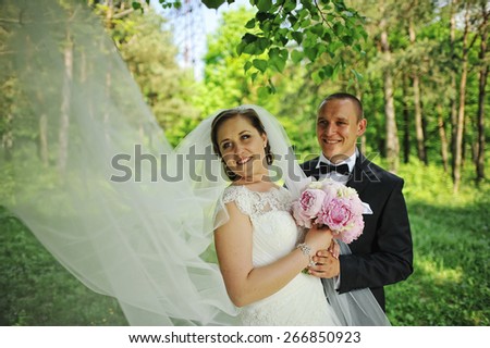 Wedding couple under the tree with big bridal veil
