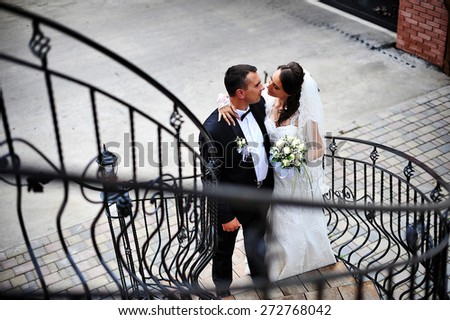 wedding couple kissing at the wrought iron stairs