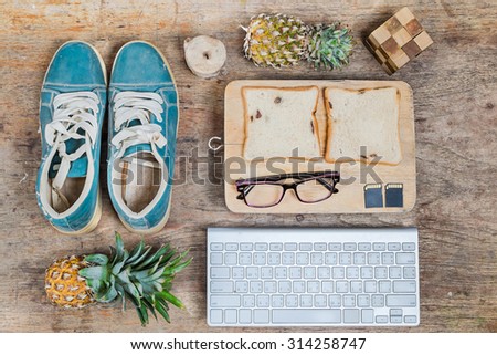 office wooden table with computer keyboard and memory card with slice of bread and glasses, pineapple, top view