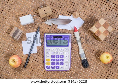 office wooden table with calculator and computer mouse with paint brush, Feather, pencil and paper, top view