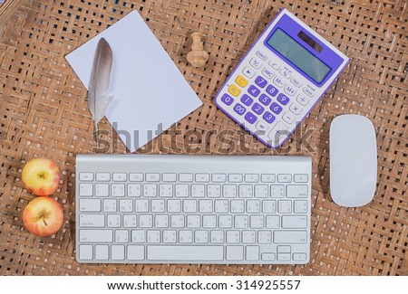 office wooden table with computer keyboard and computer mouse with paint brush, Feather, pencil and paper, top view