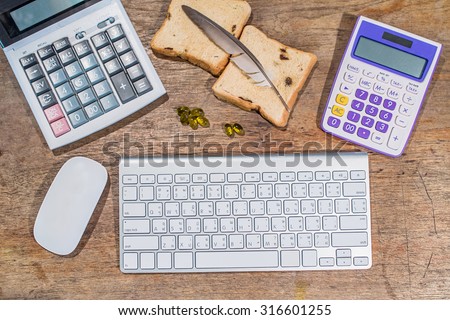 office wooden table with computer keyboard and computer mouse with Calculator, Slice of bread, and Cod liver oil omega 3 gel capsules, top view