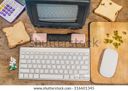 office wooden table with computer keyboard and computer mouse with television and Calculator, Dumbbell, Cod liver oil omega 3 gel capsules on chopping board, top view