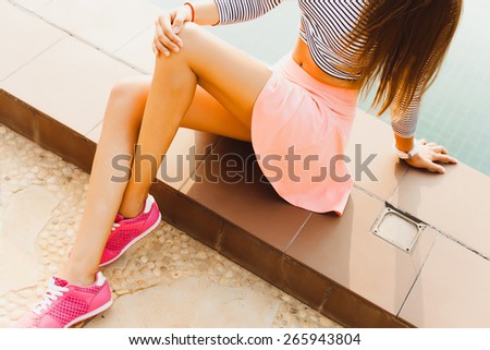 beautiful  woman in fitness clothes,sitting near pool.Wearing cool pink sport shoes.having  fun,sunshine portrait,summer outfit,summer pink skirt,sunshine outfit of summer girl near the pool.