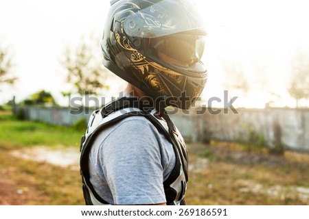 Young  sportsman posing on helmet opposite the sunset.Motocross man,sportsman on motorcycle wear helmet,motocross clothes ,cool motorcycles man in sunglasses and helmet