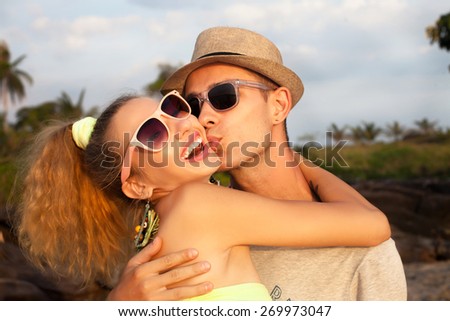 Fashion lifestyle portrait of young perfect  beautiful couple relaxed on their vacation, wearing sunglasses and vintage clothes.Kissing and  having fun together.Hugging each other,summer style,outfit.