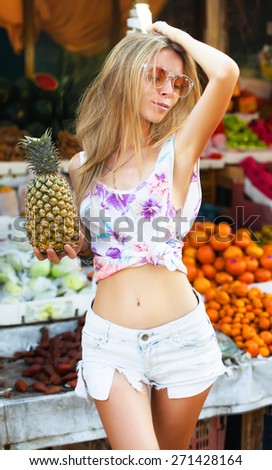 Beauty Model Girl takes Pineapple. Beautiful Joyful teen girl with freckles.Having fun on fruit market.natural beauty,funny emotions.Summer mood street style,fashion look.Going  crazy and having fun.