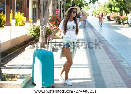 Very emotional woman having fun in airport.Happy of her new trip, screaming laughing and having fun with bright luggage,enjoy travel together.Summer mood,urban background,fashion look.Wear summer hat