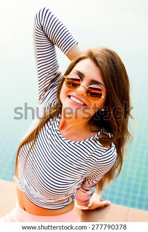 Indoor fashion portrait of young curled brunette beautiful woman with bright make up having fun and cute smiling, wearing sexy casual sportive outfit, urban background, bright colors.