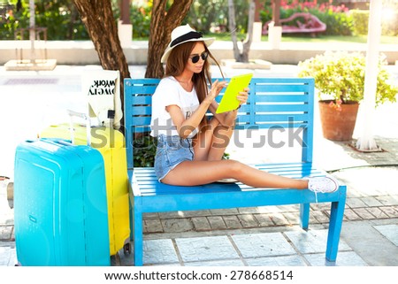 close up summer portrait of women using tablet at outdoor for relax time in park near airport,beautiful woman waiting for flight departure sitting on suitcase and use tablet,street background