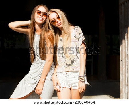 Close up fashion portrait of two sisters hugs and having fun together, wearing bright summer dresses and stylish mirrored sunglasses, best fiend enjoy amazing time together .Summer mood