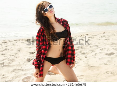 Fashion portrait of girl in cool bikini on the beach.Summer fashion portrait of woman with tanned fit sexy body,wearing cool bright bikini jewelry and sunglasses,posing beach in hot summer day