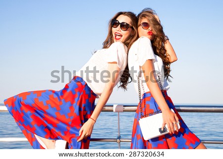Beautiful sexy girls with wavy hair in a bright multi-colored suit on the wide shoulder straps with rings bracelets accessories,Two Friends Scream With Excitement