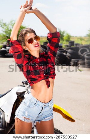 Happy Hispanic Teen Girl Rides,Raises Arm in The Air Young.sexy woman,wear denim summer outfit,mirrored sunglasses,perfect glowing tan skin, happiness,trim,athletic figure,perfect female body