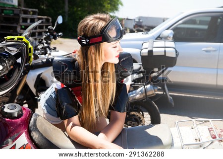 Outdoor summer portrait of pretty blonde sexy woman posing on off-road motorcycle in summer,equipment, sports equipment ,freestyle ride,dirty motorcycle riding,racing,woman preparing for a competition