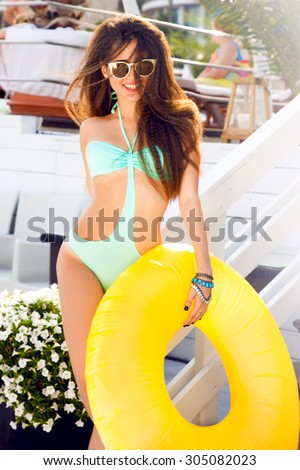 Outdoor lifestyle laughing portrait of young happy,smiley teen girl with playful mood and bright bikini,fun near pool,vacation.Nice sunny summer hot day.Sunbathing at pool,party,accessory store,nails
