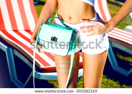 Street style fashion details,bright blue romper,elegant white clothes,backpack and trendy jewelry,posing on the street,bright colors.clutch,bright handbag,advertises bags.luxury,party clothes
