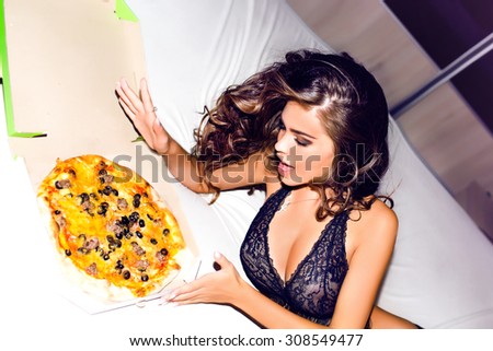 Lifestyle portrait of surprised woman,colored lingerie posing on bedroom and eating pizza,girl order,takeaway food,no diet.surprised girl having fun,laughing woman,opening mouth.party time,amazing