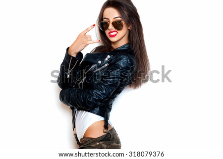 Young woman with sunglasses giving the Rock and Roll sign.White background, not isolated.black leather jacket.Woman dancing and going crazy,fancy woman,classic aviator sunglasses,fashionista,red lips Stock fotó © 