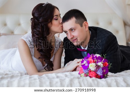 The bride kisses bridegroom\'s forehead, holding hands