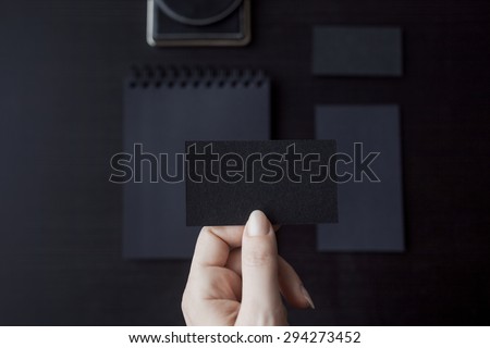 Set of black mockups on dark background,  female hand holding a business card