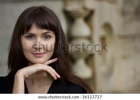 young beautiful girl against an impressive stone wall