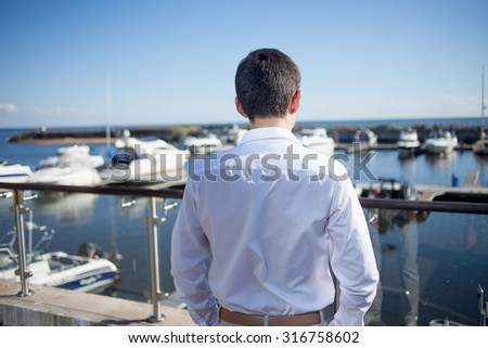 young man near the yacht club,  view from  back