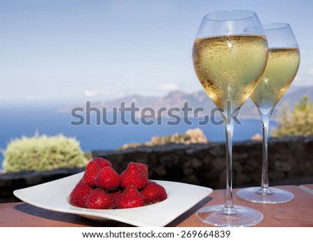 romantic drink in corsica with strawberries and white wine in two glasses and a view on the sea